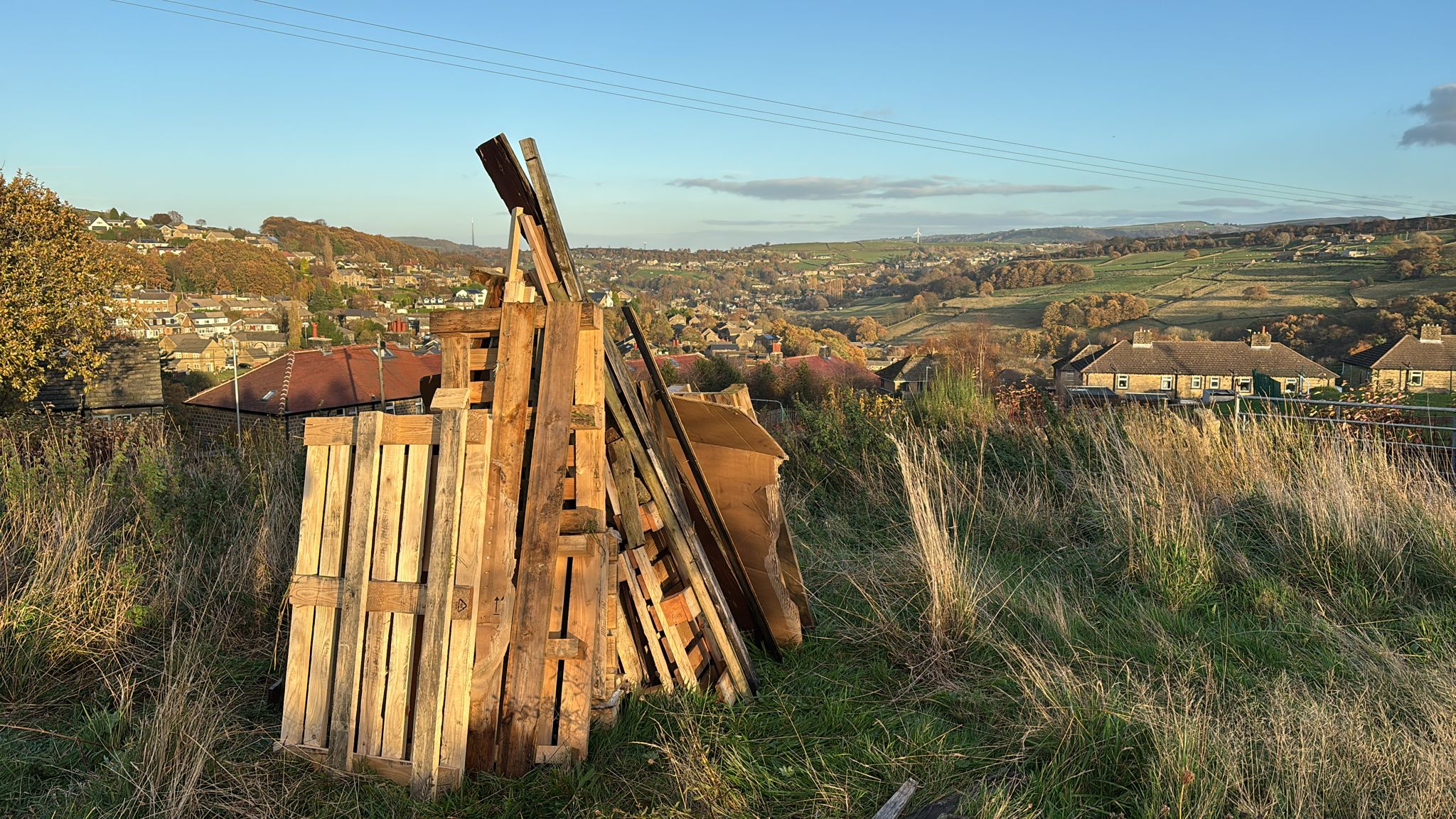 Wood stacked up for a bonfire in a field.